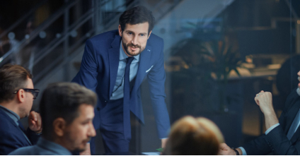 Hombre de cabello canoso con una notebook abierta y mirando una hoja de papel